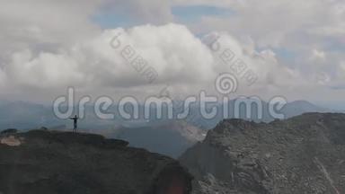 一名男子站在山顶的空中射击。 年轻的登山者在爬山后高兴地举手。